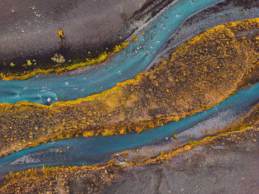Drone shot river running trough black volcanic sand